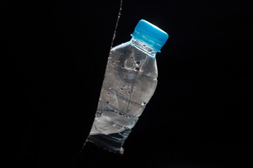 Plastic bottle hanging for drinking to quench thirst on black background.