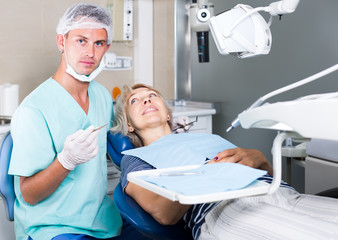 young male dentist with female patient during checkup in dentistry