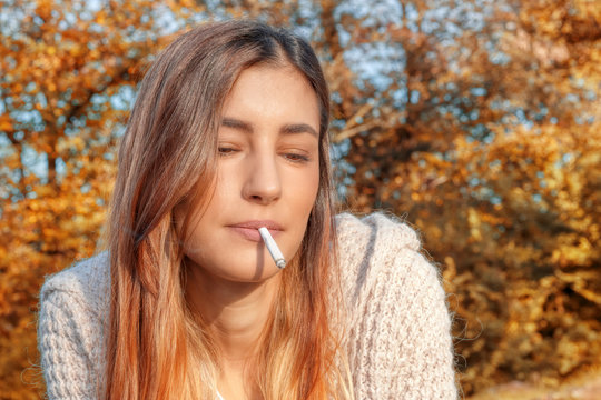 Una ragazza che fuma una sigaretta al sole