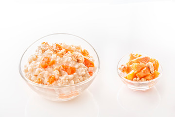 Oatmeal with pumpkin and nuts in a glass plate on a white background. Close-up. Copy space