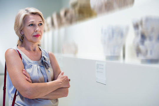 Positive woman in art museum near the antique classical sculpture