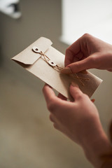 A female woman hand hold open a envelope and post card on a light background at home.