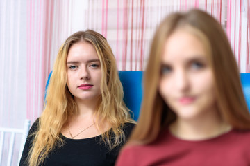 Fototapeta premium The concept a couple of beautiful young lesbian girls are talking in a room sitting on a sofa.