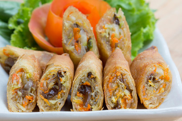 Deep fried spring rolls, Por Pieer Tod or Fried spring rolls (Thai Spring Roll) on white dish on wooden table,Thai and Chinese people.