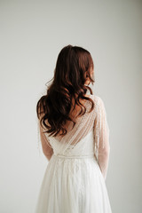 Fototapeta premium morning of the bride. the bride is standing back, beautiful curls, a gentle wedding dress studio, white background