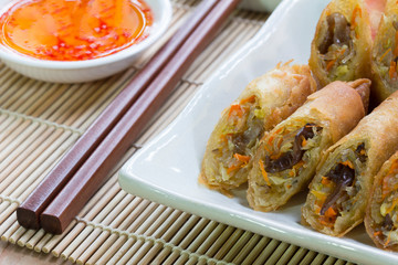 Deep fried spring rolls, Por Pieer Tod or Fried spring rolls (Thai Spring Roll) on white dish on wooden table,Thai and Chinese people.