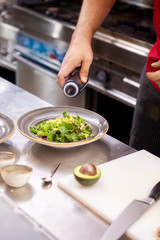 Chef seasoning delicious salade in his restaurant kitchen