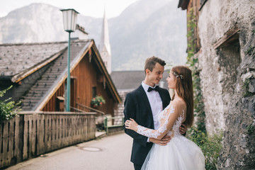 A beautiful wedding couple walks in a fairy Austrian town, Hallstatt.