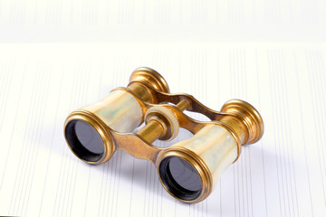 antique theater opera binoculars rest on an empty music score with copy space