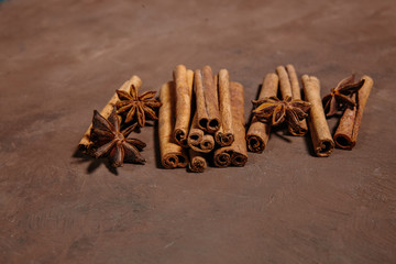 Brown background and composition of aromatic spices. Cinnamon sticks and anise stars