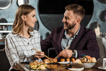 Happy beautiful couple amorously looking at each other while having dinner in restaurant