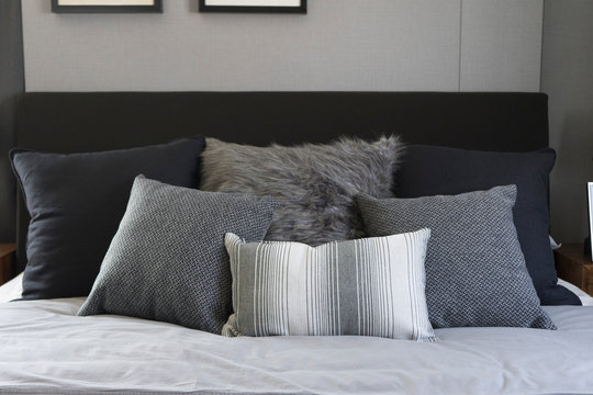 Bed with white and grey linens and a lot of pillows.