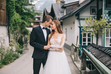 A beautiful wedding couple walks in a fairy Austrian town, Hallstatt.