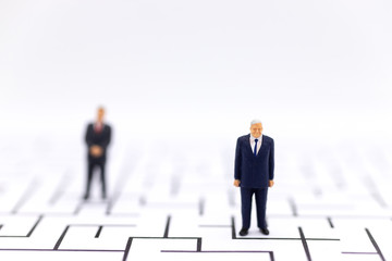 Miniature people: Businessman standing with a maze to background. Image use for find solution, business concept.