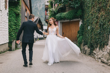Fototapeta na wymiar A beautiful wedding couple walks in a fairy Austrian town, Hallstatt.
