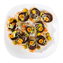 Tasty canapes with blood sausage, bread, olives and onion  at plate