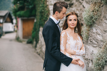 A beautiful wedding couple walks in a fairy Austrian town, Hallstatt.