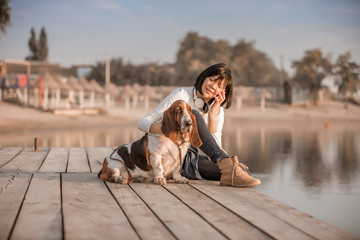 Woman sitting by the river with her dog and talking on phone