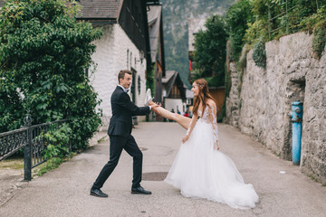 A fun wedding couple joking each other and walks in a fairy Austrian town, Hallstatt.