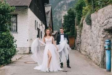 A fun wedding couple joking each other and walks in a fairy Austrian town, Hallstatt.