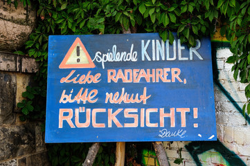 handgemaltes Hinweisschild, spielende Kinder, Liebe Radfahrer, nehmt R&uuml;cksicht