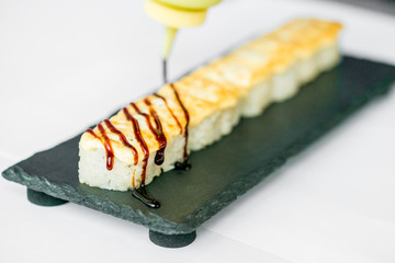 Putting sauce on uncut Japanese sushi roll