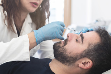 Female doctor putting fillers on man patient