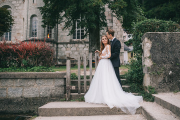 Fototapeta premium A beautiful wedding couple posing on a background old cathedral in a fairy Austrian town, Hallstatt.