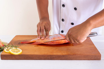 Chef cutting fish in the kitchen.
