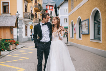 A beautiful wedding couple walks in a fairy Austrian town, Hallstatt.