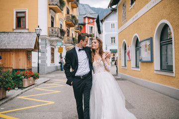 A beautiful wedding couple walks in a fairy Austrian town, Hallstatt.