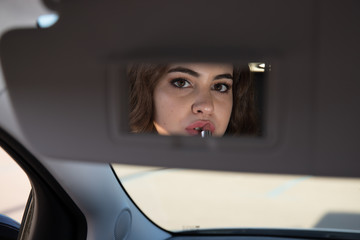 girl putting makeup on the car