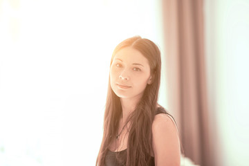 Naklejka premium portrait of a beautiful young woman at the window at sunset