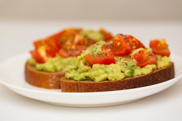 Avocado toast. Healthy toast with avocado mash and cherry tomatoes on a plate.