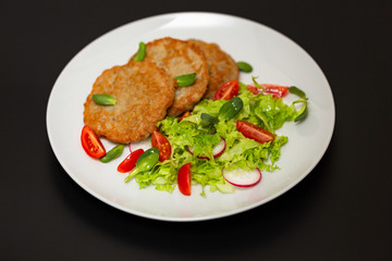Potato pancakes with fresh mix of salad on a plate close-up.