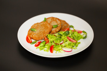 Potato pancakes with fresh mix of salad on a plate close-up.
