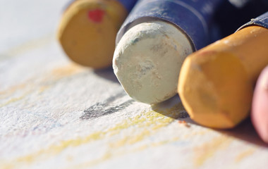 sticks oil pastels, wrapped in paper, lie on painted paper