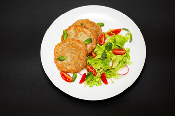 Potato pancakes with fresh mix of salad on a plate close-up.