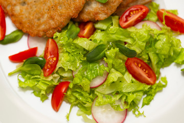 Potato pancakes with fresh mix of salad on a plate close-up.
