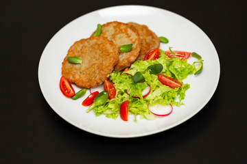 Potato pancakes with fresh mix of salad on a plate close-up.