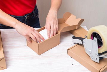 Woman packing cardboard boxes , picking and puttind products