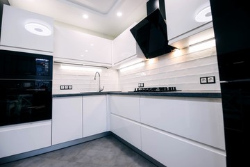  interior of a modern compact white kitchen with gas stove, oven, refrigerator. built-in furniture household appliances.