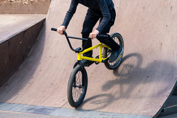 Young cyclist down the ramp. Guy is rolling down the bike from ramp.