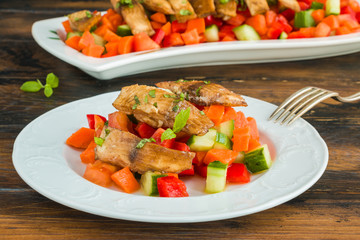 Tilapia fish fillet marinated in ginger and garlic sauce and roasted with olive oil. Fresh vegetable salad and whitefish on white plate