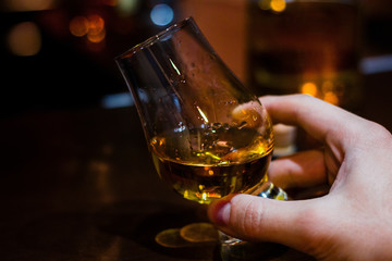 hand holds whiskey in a special glass for tasting with space for text