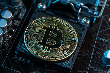 Golden Bitcoin Cryptocurrency on computer circuit board CPU. Macro shot.