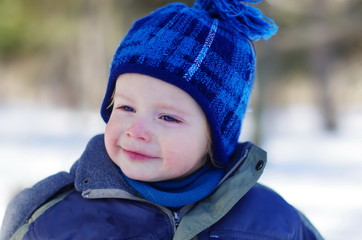 winter portrait of a cute, funny, emotional boy with bright blue eyes and a blush on his cheeks