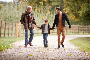 Fototapeta premium Grandfather With Son And Grandson On Autumn Walk In Countryside Together