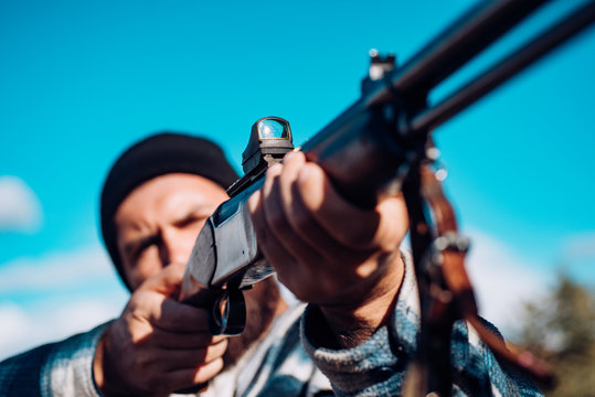 Hunter hanting with laser sight. Collimating sight. Hunter with shotgun. Poacher in the Forest. Big game.