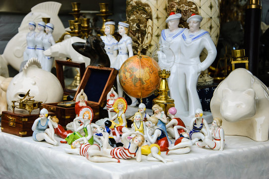 Figurines Of Ladies In Swimsuits, Antique Globe, Figurines Of Sailors, Etc. For Sale At Flea Market In Paris. Flea Markets Are Very Popular Type Of Entertainment In France. Vacation Concept.